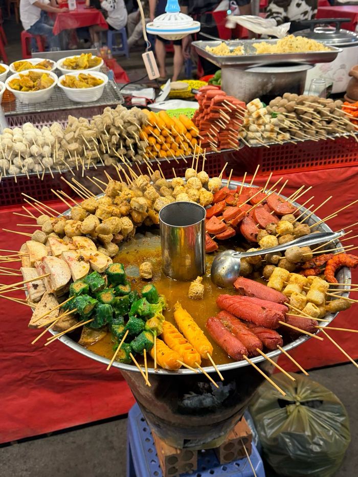 A hot pot surrounded by skewers at a night market stall