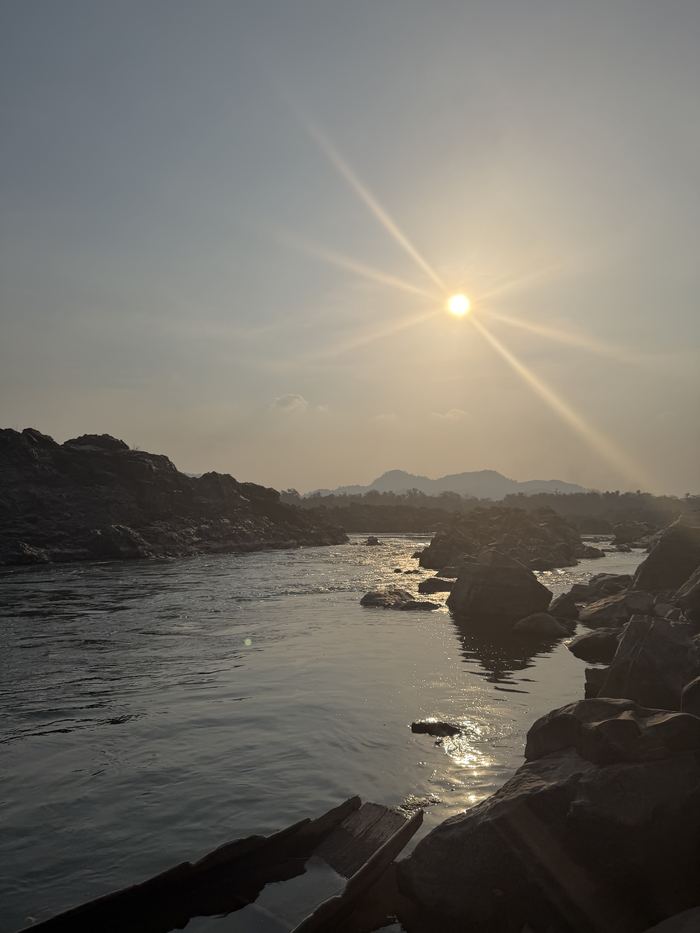 The sun setting over the Mekong with rocks in the foreground