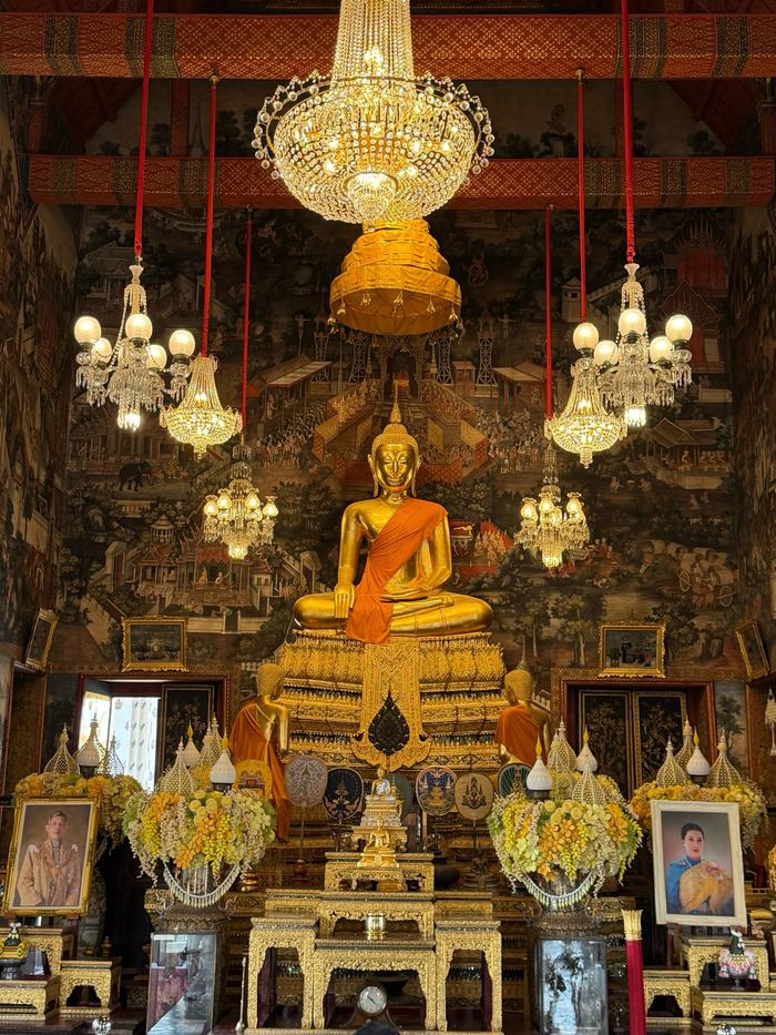 A golden Buddha under chandeliers inside a temple