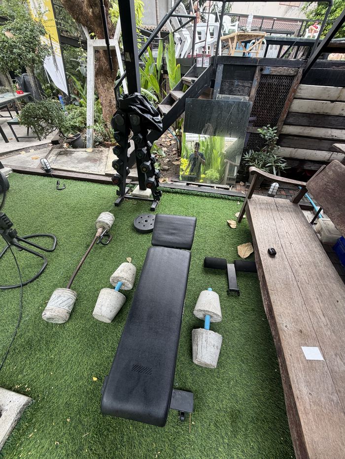 An outdoor gym with a bench and homemade concrete weights on artificial turf