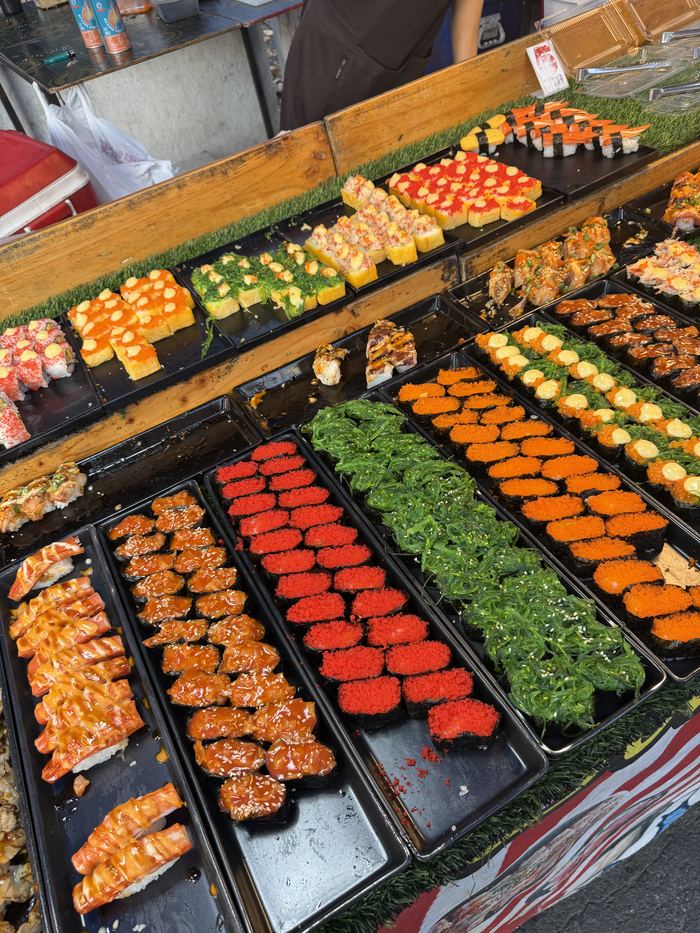 Trays of colorful sushi at a street stall