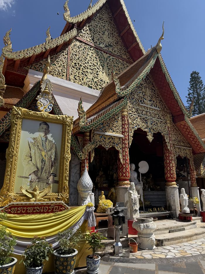 An ornate temple entrance with a portrait of the Thai king