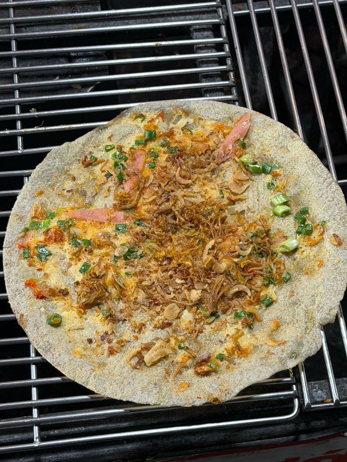 Banh trang nuong cooking on a grill