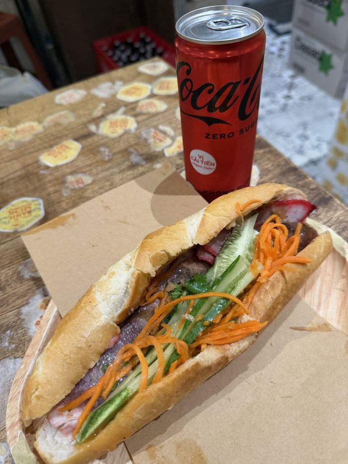 A banh mi sandwich next to a Coke Zero