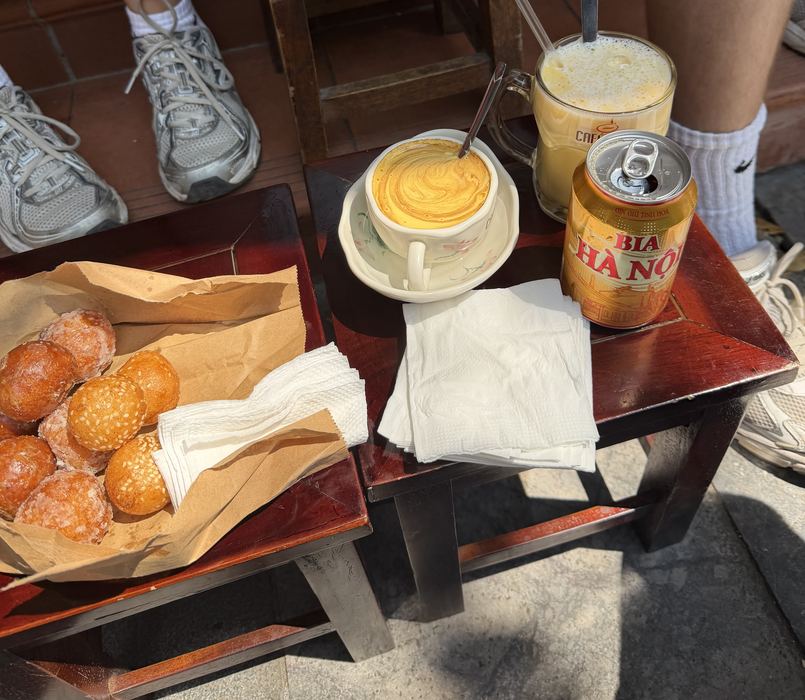 Egg coffee, egg beer, a can of Bia Hanoi, and donuts on a low table