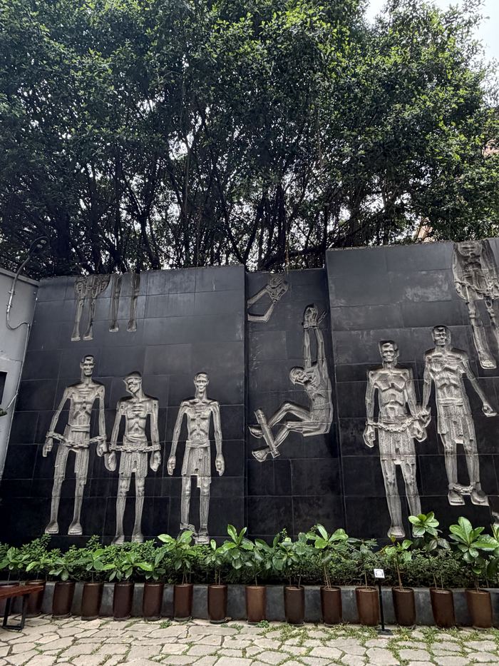 A dark stone wall with relief sculptures of prisoners