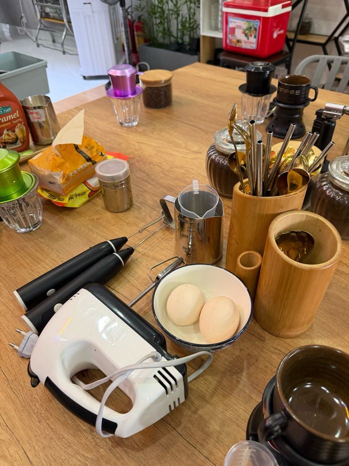 Coffee-making tools, eggs, and a hand mixer on a table