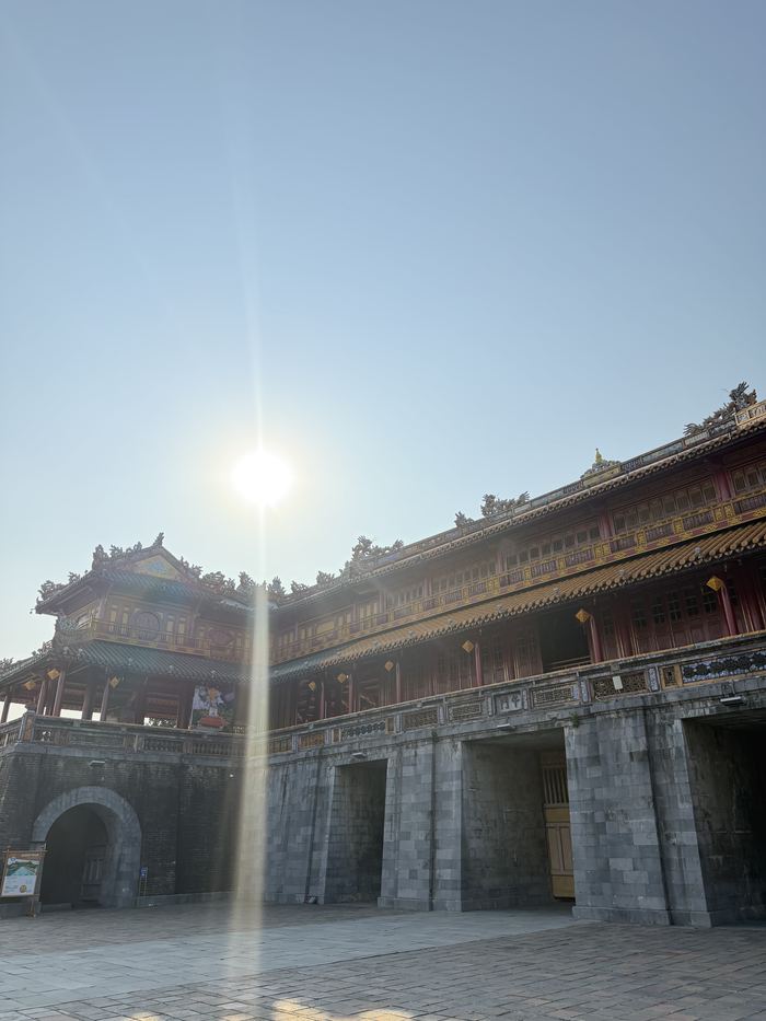 A large gate building with the sun shining behind it