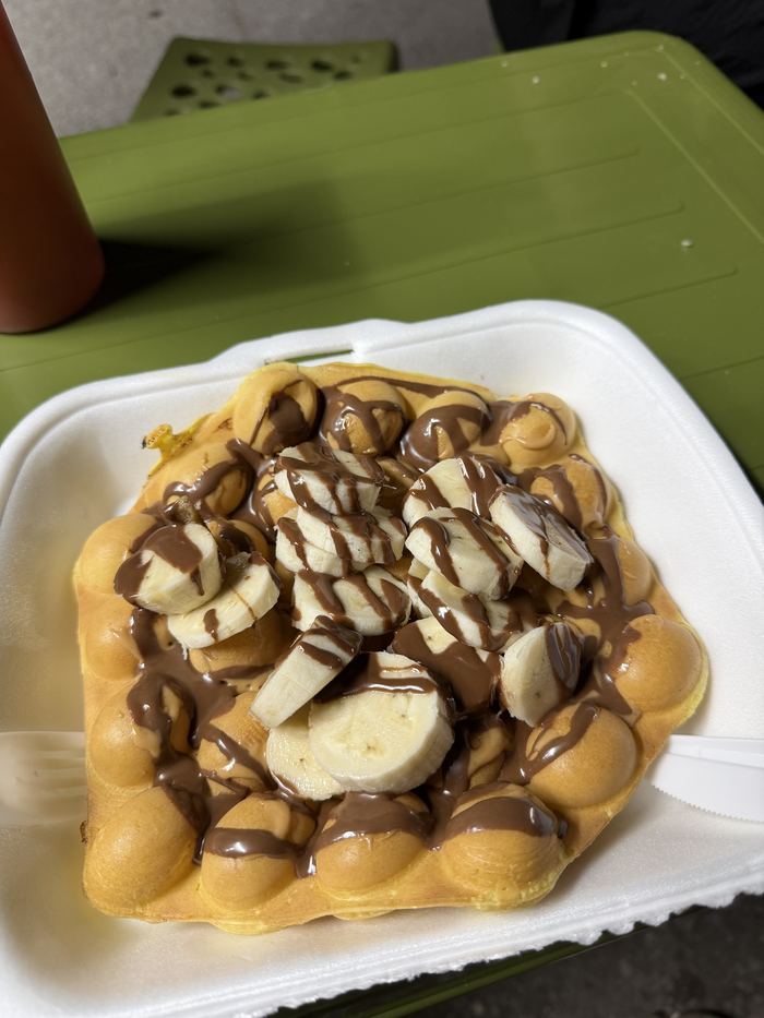 A bubble waffle topped with banana and chocolate