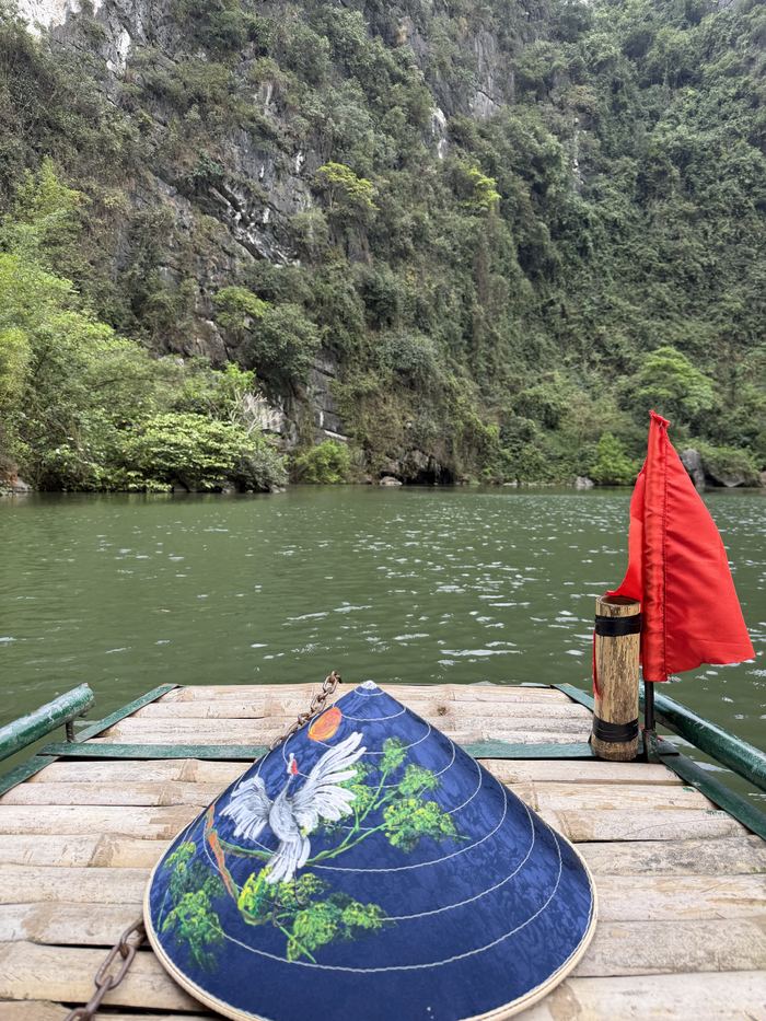 A conical hat on the bow of a boat on a green river