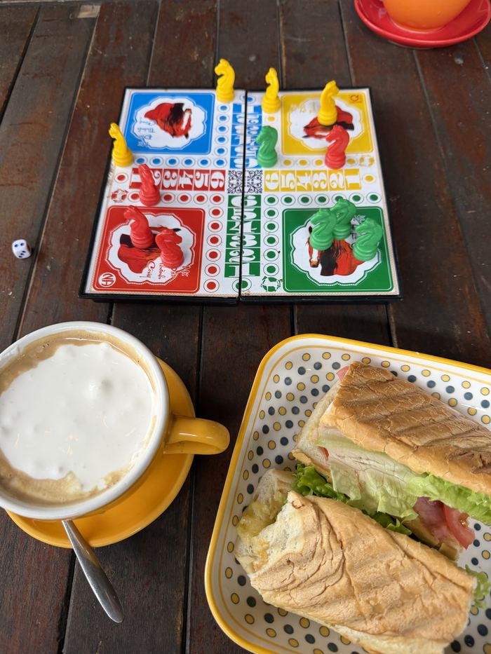 A board game, a coffee, and a toasted sandwich on a table