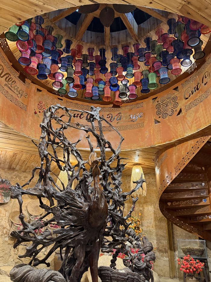 A ceiling of colorful hanging pots above a tree-root sculpture