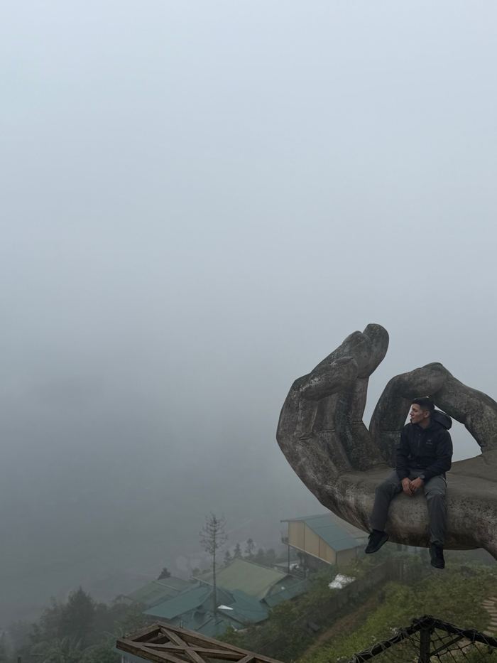 Sitting on a giant stone hand sculpture in the fog